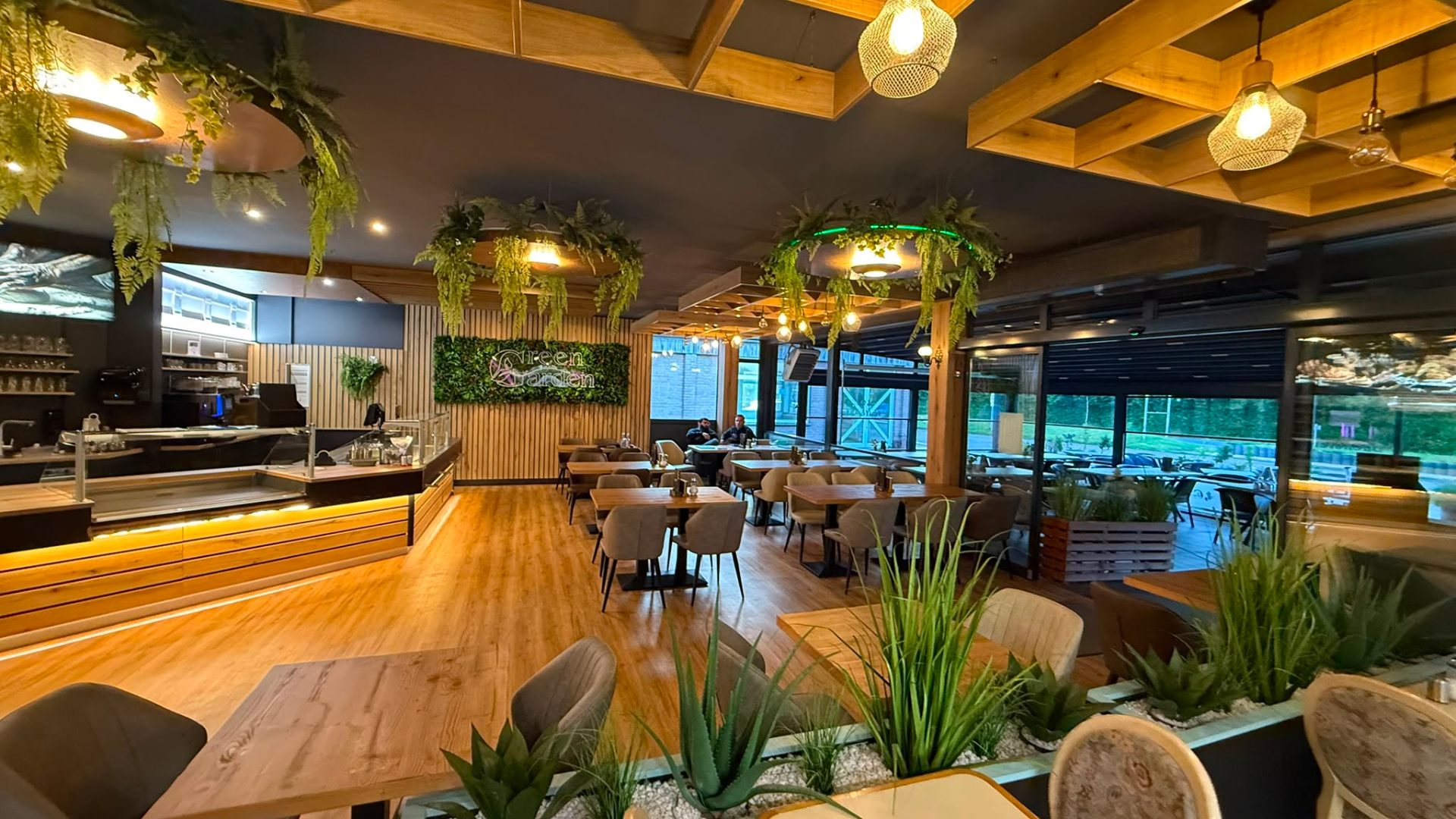 Green Garden Café interior with warm wood, hanging ferns and moss wall